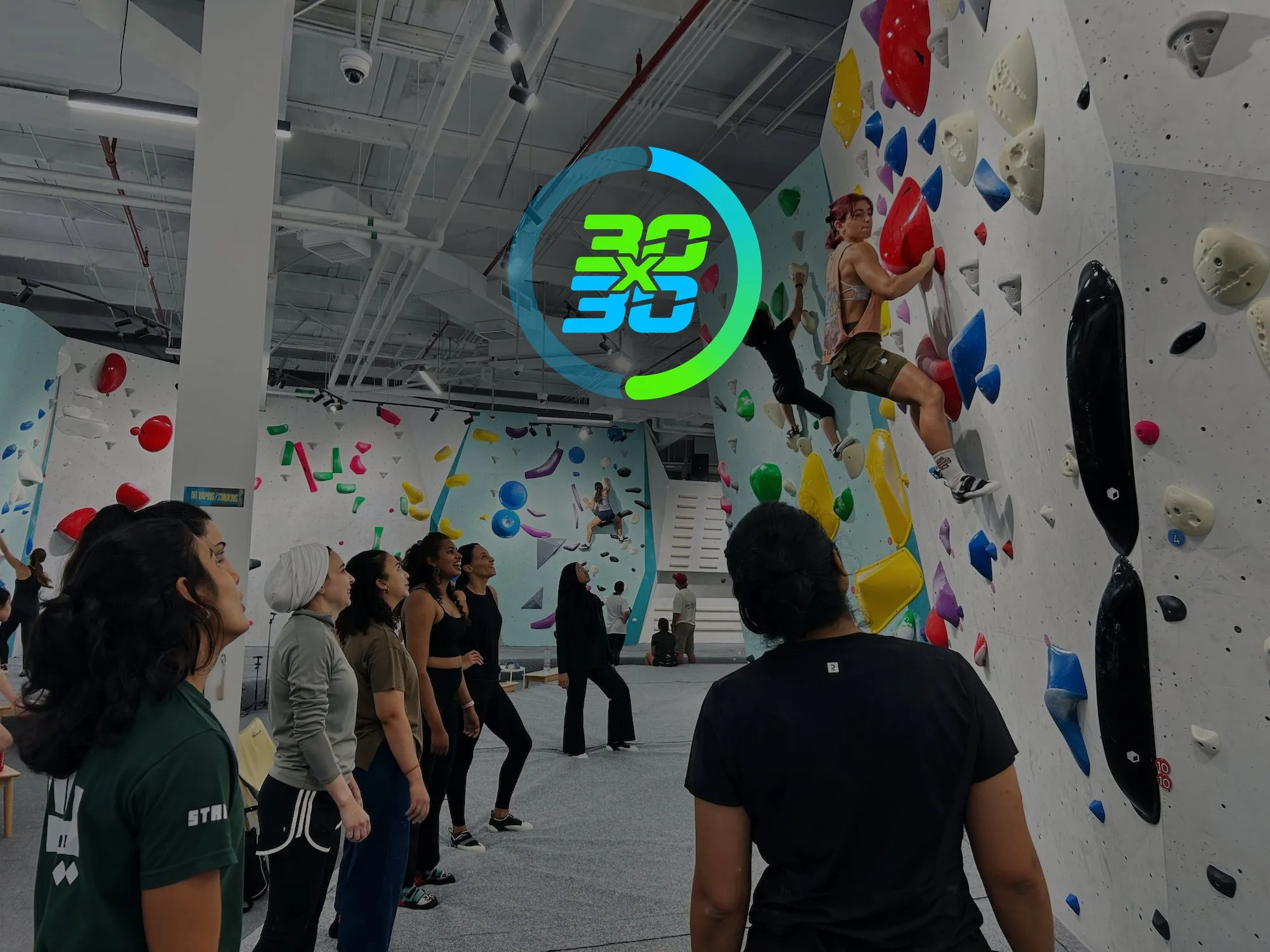The 30x30 Dubai Fitness Challenge logo over a GoClimb session, a group of new climbers watching two climb the wall