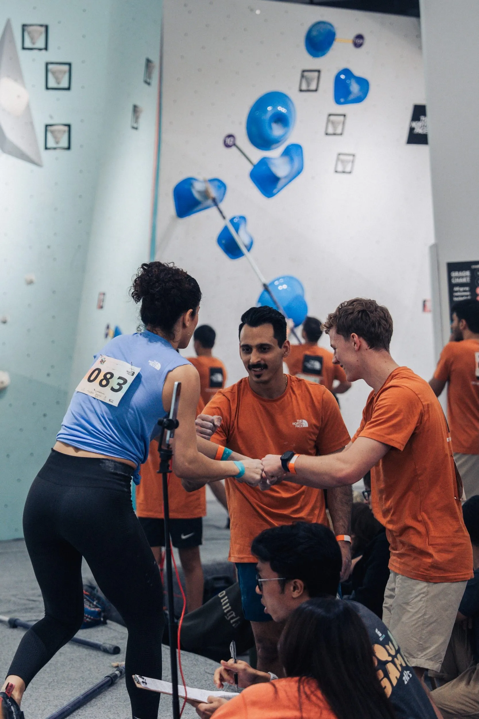 A climbing team topping out a boulder route and exchanging fistbumps