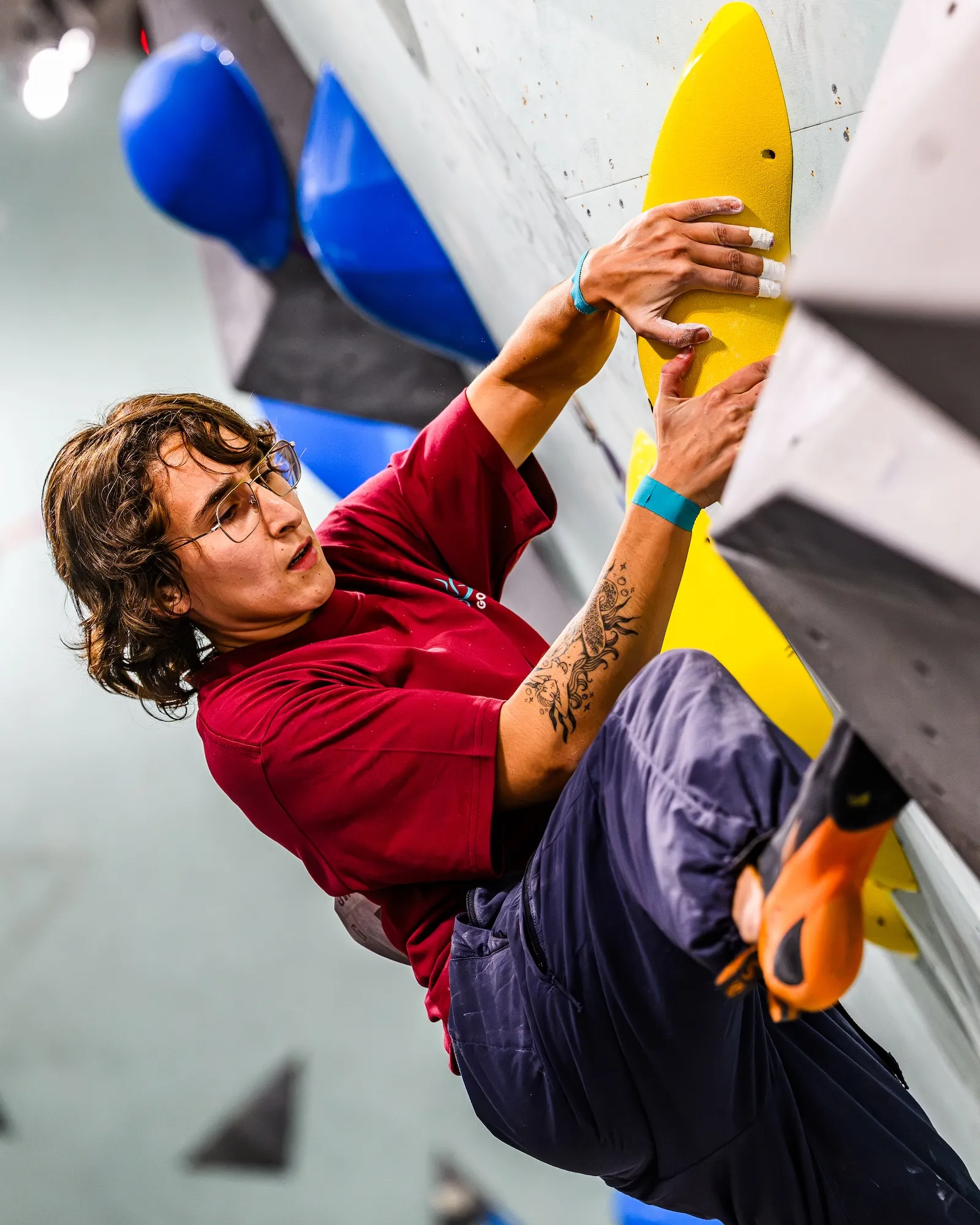 A competitor locked off on a steep line, pulling through to a yellow hold